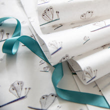 Load image into Gallery viewer, Reams of illustrated dragonfly tissue paper with turquoise ribbon curled over. 