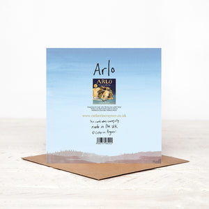 Back of blue square happy birthday card, featuring lion illustration of Arlo, standing on matching brown envelope.