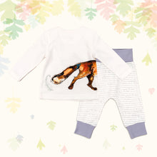 Load image into Gallery viewer, Baby gift set comprising a white top showing the tail of an illustrated wraparound fox print and matching bottoms with purple cuffs, on a backdrop of pastel leaves. 