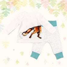 Load image into Gallery viewer, Baby gift set comprising a white top showing the tail of an illustrated wraparound fox print and matching bottoms with ocean blue cuffs, on a backdrop of pastel leaves. 