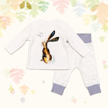 Load image into Gallery viewer, Baby gift set comprising a white top featuring a front and back illustrated hare print and matching bottoms with purple cuffs, on a backdrop of pastel leaves.