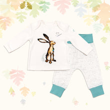 Load image into Gallery viewer, Baby gift set comprising a white top featuring an illustrated hare print and matching bottoms with ocean blue cuffs, on a backdrop of pastel leaves. 