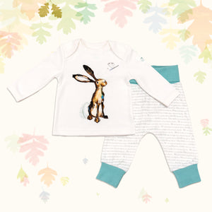 Baby gift set comprising a white top featuring an illustrated hare print and matching bottoms with ocean blue cuffs, on a backdrop of pastel leaves. 