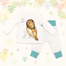 Load image into Gallery viewer, Baby gift set comprising a white long-sleeved top showing back of an illustrated owl print and matching bottoms with ocean blue cuffs, on a backdrop of pastel leaves. 