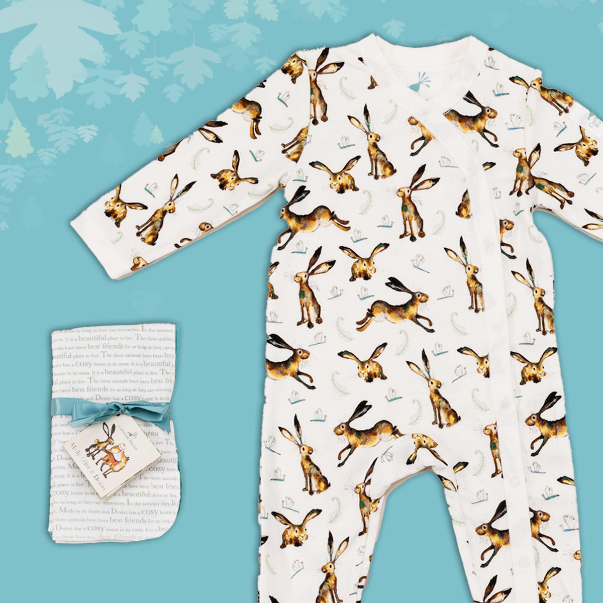 Baby gift set comprising a white babygrow featuring an illustrated hare and dragonfly print and matching dribble cloths tied in turquoise ribbon, on a blue backdrop with decorative  leaves. 