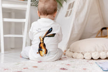 Load image into Gallery viewer, Baby sat facing away while wearing the Molly Hare top, showing the illustration on the back of Molly Hare from behind. 