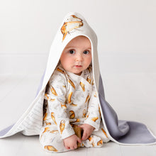 Load image into Gallery viewer, 6 month old baby wearing the olive owl babygrow and the matching hooded blanket looking into the camera. 