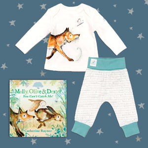 Baby gift set featuring a book from the Molly, Olive and Dexter series by Catherine Rayner, 'You Can't Catch Me!' and a matching fox pyjama set laid on a midnight blue backdrop with silver stars. The pyjama set comprises a white long-sleeved top featuring an illustrated wraparound fox print and matching bottoms with blue cuffs.