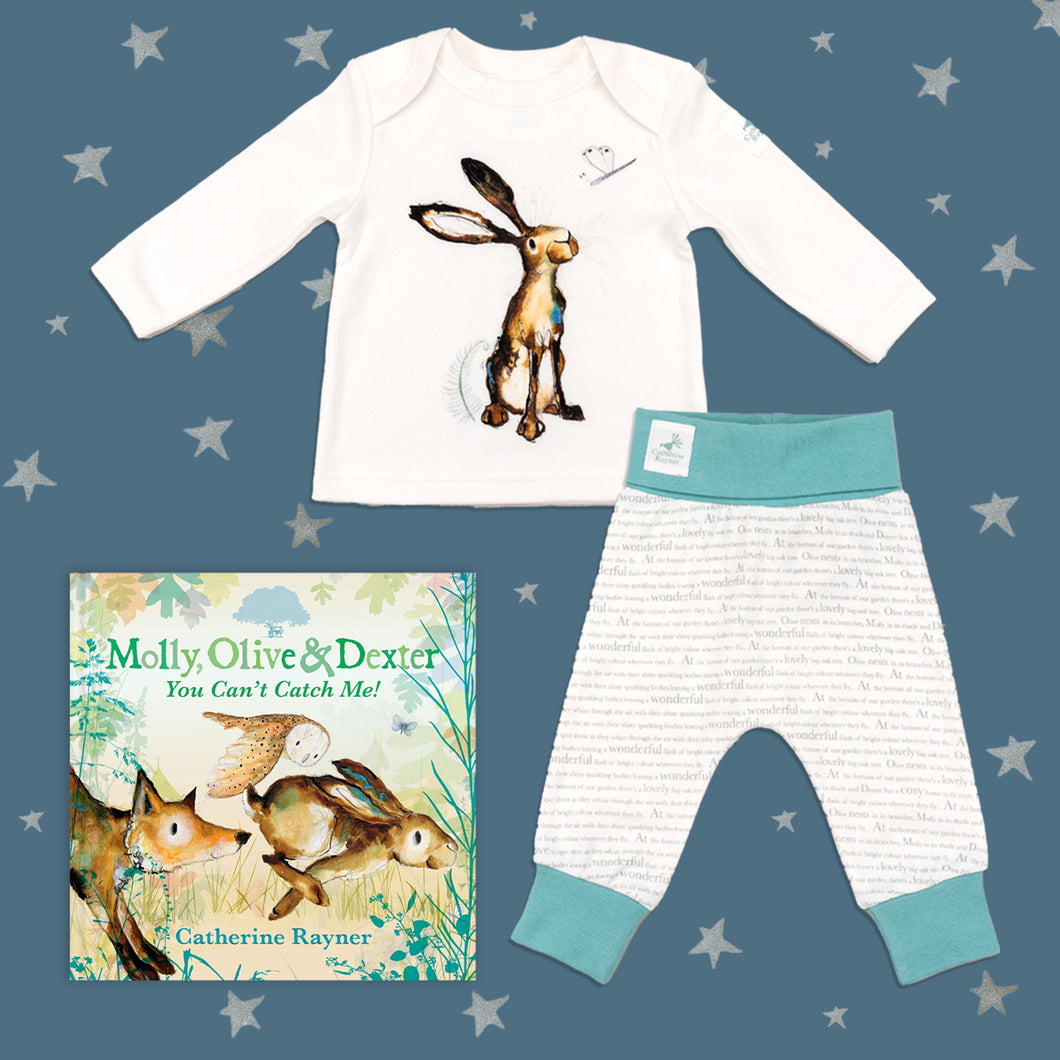 Baby gift set featuring a book from the Molly, Olive and Dexter series by Catherine Rayner, 'You Can't Catch Me!', and a matching hare pyjama set laid on a midnight blue backdrop with silver stars. The pyjama set comprises a white long-sleeved top featuring an illustrated wraparound hare print and matching bottoms with blue cuffs.