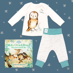 Baby gift set featuring a book from the Molly, Olive and Dexter series by Catherine Rayner, 'You Can't Catch Me', and a matching owl pyjama set laid on a midnight blue backdrop with silver stars. The pyjama set comprises a white long-sleeved top featuring an illustrated wraparound owl print and matching bottoms with blue cuffs.