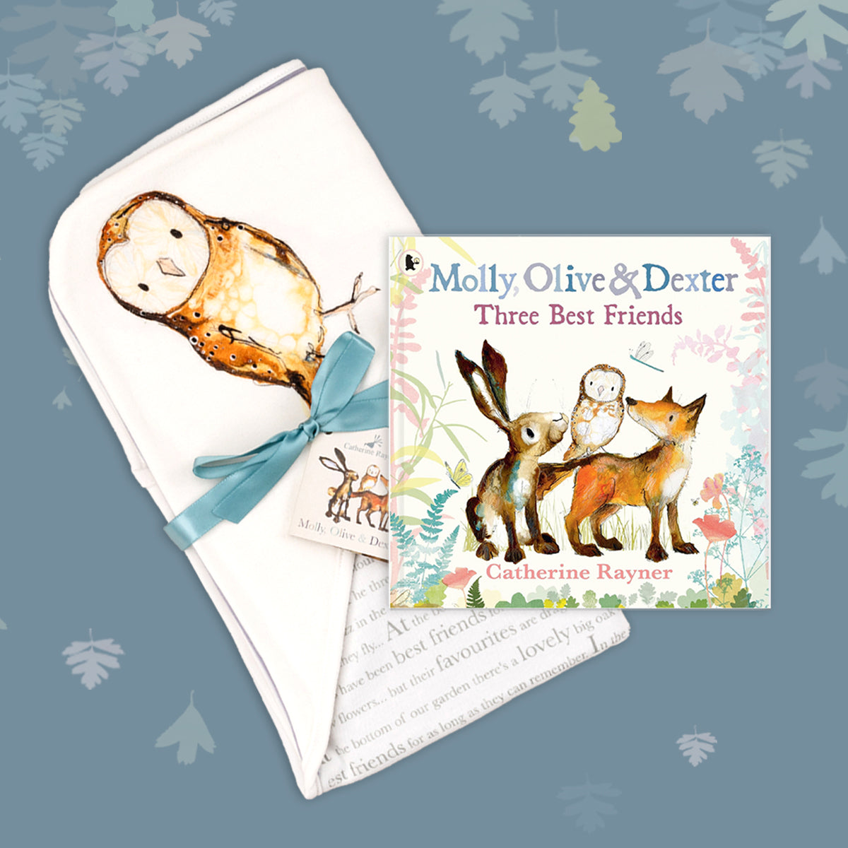 Baby gift set featuring a book from the Molly, Olive and Dexter series by Catherine Rayner, 'Three Best Friends', and a matching owl blanket laid on a dusty blue backdrop with pastel leaves. The blanket has a hood featuring Olive Owl and is wrapped with a turquoise ribbon. 