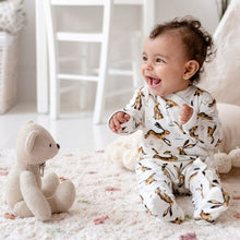 Load image into Gallery viewer, One year-old baby girl sat up laughing wearing Molly Hare repeat print babygrow. 