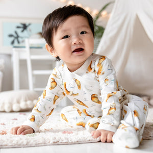 One year old baby sat leaning forward wearing the illustrated Olive Owl Babygrow.