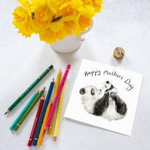 A Mother's Day Card featuring a watercolour pencil illustration of a mummy and baby panda laid on a tabletop alongside some daffodils and coloured pencils. 