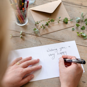 Writing a personal message inside a christmas card on a wooden desk