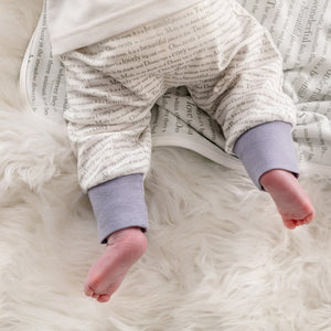 Close-up on a baby wearing Dusky heather storytime joggers, showing the story text print and dusky heather cuffs. 