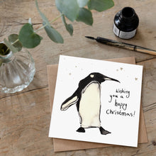 Load image into Gallery viewer, Christmas card featuring illustration of Pablo Penguin laid flat on a wooden table with a matching brown envelope. 