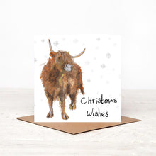 Load image into Gallery viewer, Square white Christmas card featuring Adrian the highland cow surrounding by snowflakes standing on top of the matching brown envelope. 