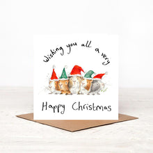 Load image into Gallery viewer, White square illustrated guinea pig Christmas card stood on matching brown craft envelope. 