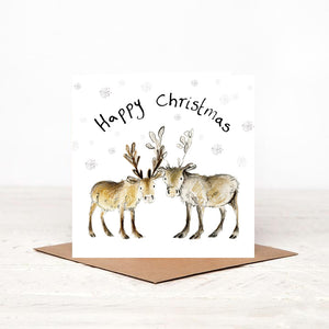 Square illustrated baby reindeer christmas card stood on matching brown craft envelope. 