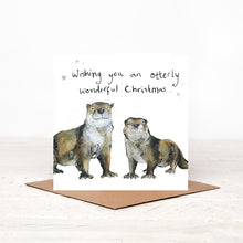 Load image into Gallery viewer, Square illustrated otters Christmas card stood on matching brown craft envelope. 